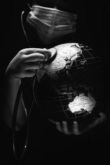 Kid hold globe put stethoscope on sphere, face covered in mask on black background. Ecological...