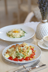 Appetizing Caesar salad on a white plate. Provence-style table serving