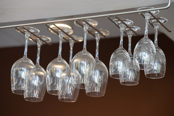 empty wine glasses are hanging on stainless steel bar rack in kitchen room.
