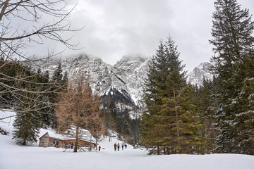 Tourists by the timber hut in Mala Laka Valley (Dolina Malej Laki) nearby Zakopane in Tatra mountains.