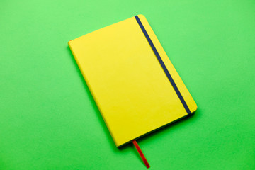 Flat lay, yellow notebook with green background