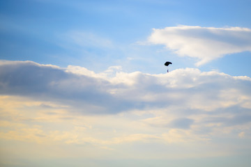 Sunset sky, paratroopers soar among the clouds. Warm summer evening in nature.
