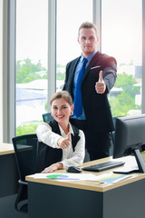 Young smart businessman and businesswoman working in the office, they give the thumbs up