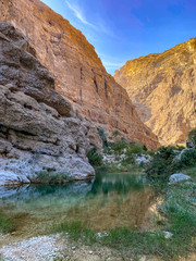 Fototapeta na wymiar Wadi Shab river canyon, Sultanate of Oman. Natural mountain landscape with green water river and vertical rocky cliffs.