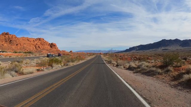4K. POV view of car driving on road of highway at day in USA. Drive on an empty road in the dark evening. Asphalt with yellow line at new road in Valley of Fire. Nevada state.