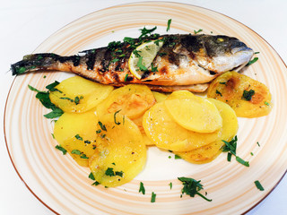 Grilled sea bass served with fried potatoes slices cooked in olive oil for eating a mediterranean meal