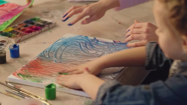 Creative children. Out-of-school activities. Inspired girl mother finger painting together.