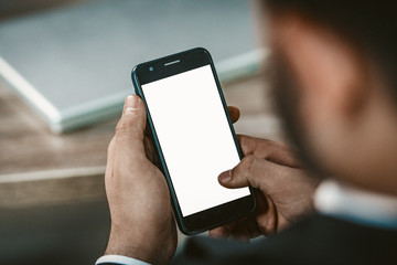 A Cell Phone In Businessman's Hands. Closeup Of Man's Hand Holding A Smartphone With White Blank Screen, Toned Image