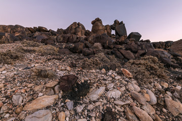 A textured rocky landscape after sunset with interesting rock formations in the foreground, taken in the Richtersveld National Park, South Africa.
