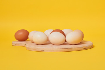 Eggs on a yellow background. Chicken eggs on a wooden board