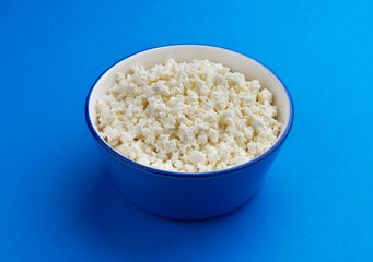 Cottage cheese in bowl on blue background