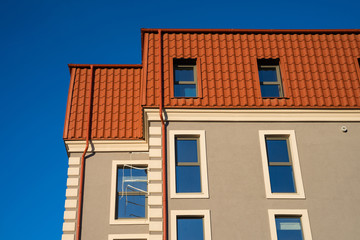 Newly installed red metal roof top and building construction frame rain gutter system.