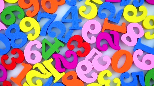 Colorful numbers are scattered and slowly rotate on a white background. The numbers are wooden, bright, and of various colors.