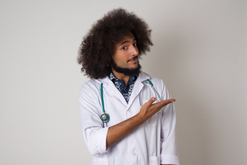 Positive glad doctor male says: wow how exciting it is, has amazed expression, shows something on blank space with open hand over isolated gray background. Advertisement concept.