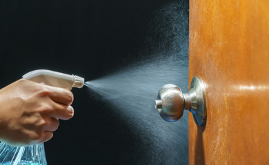 Cleaning door knob with alcohol spray for  Covid-19 (Coronavirus) prevention. - obrazy, fototapety, plakaty