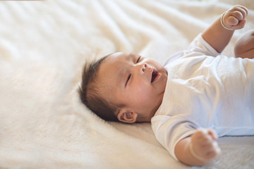 Obraz na płótnie Canvas Newborn baby lying on a soft white mattress, smiling happily.