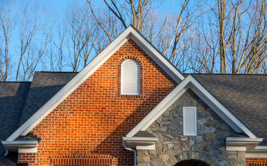 Colonial white round top and vertical wood gable vent on a brick and stone veneer facade double...
