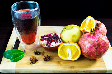 Still life of fruit. The garnet is cut on the Board. The orange is cut on a kitchen board. A glass of pomegranate juice.