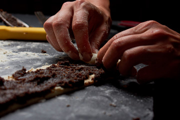 Professional Female cook sprinkles dough with flour, prepared for baked bread