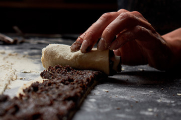 Professional Female cook sprinkles dough with flour, prepared for baked bread