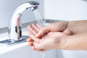 Close up of man washing hands 7 step with soap or sanitizer gel on sinks faucet with water for clean virus and bacteria, health care concept (select focus)