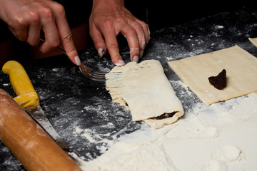 Professional Female cook sprinkles dough with flour, prepared for baked bread