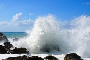 Sea waves are bouncing hard onto rocks.