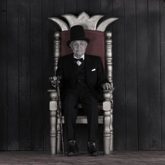 Fototapeta na wymiar old gentleman on a chair on a black background