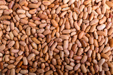 Natural background of many fresh organic red beans in warm light, top view or flat lay of healthy food, brown monochrome indoor background photographed with selective focus