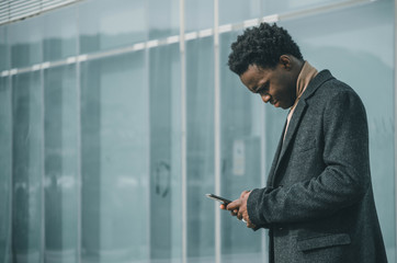businessman standing in front of office building with his smartphone