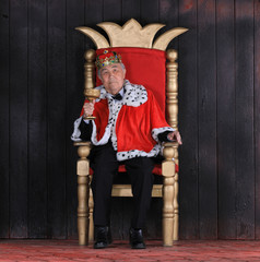 old king with a crown on the royal throne on a black background