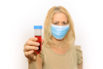 Woman with face mask holding a tube of blood. Concept of coronavirus epidemic, quarantine for public health from infections, virus test and research concept. Positive Coronavirus test blood sample.