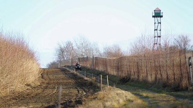 The state border is controlled by border guards on an ATV. An armed patrol on an ATV inspects the border and reveals illegal crossing and drug trafficking. Border patrol on the border.
