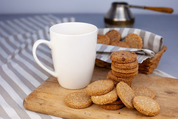 White cup with place for text. Breakfast is on the table. Cup with coffee and round homemade cookies. Mug with a drink and a snack. Mockup for designs. 