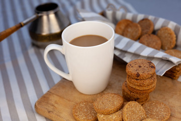 White cup with place for text. Breakfast is on the table. Cup with coffee and round homemade...
