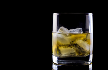 Tumbler glass with whiskey on black background