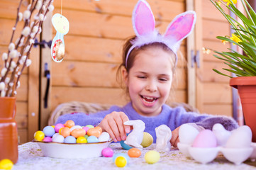 Easter. Little girl with colored eggs in her hands and chocolate colored eggs. Happy Easter holiday at home. Decor and decoration on the table. Copy space. Happy holidays