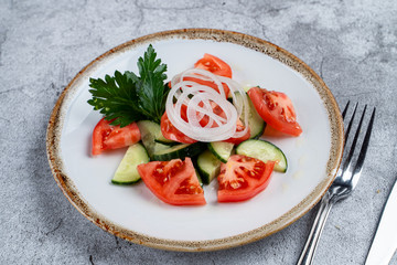 Simple summer salad with cucumber and tomato, seasoned with onion rings