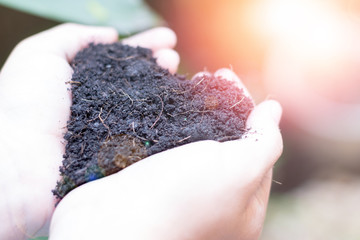 World soil day concept. Child's hand holding black soil in heart shape for environment saving.