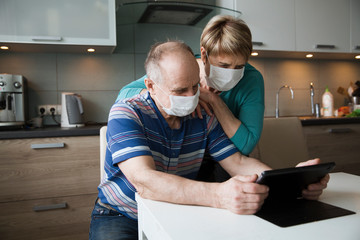 Seniors couple  wearing medical face mask and using tablet at home. quarantine. health concept....