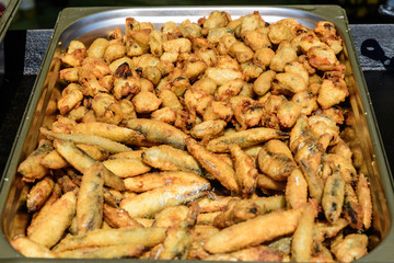 Large group of freshly fried  mussels on display for sale at a street food festival, ready to eat healthy seafood, beautiful orange monochrome outdoor background