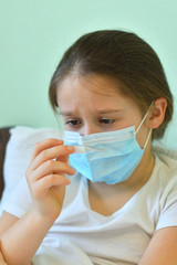 girl looks at a high-temperature thermometer.Quarantine.Blue infection preventive face mask . I virus infection in Corona virus crisis 2020. Take care kids from infection.