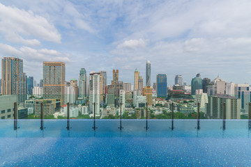 Fototapeta na wymiar Infinity Pool In Bangkok Luxury Hotel Resort Against Cloudy Sky and City Skyline