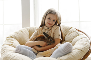 cute little girl study on the sofa in the company of rabbit 