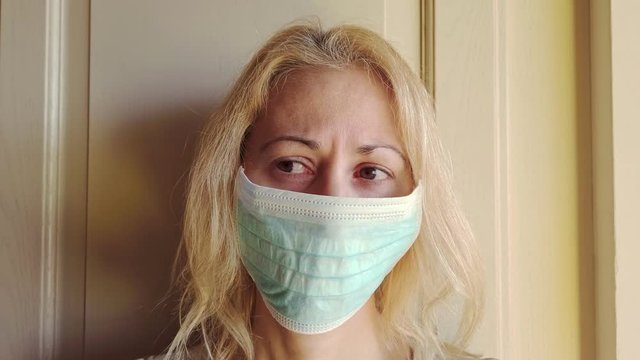 SLOW MOTION: side view of a blonde girl with a sanitary mask on white background isolated. Concept of the epidemic outbreak, quarantine for public health care and outbreak of the corona-virus.