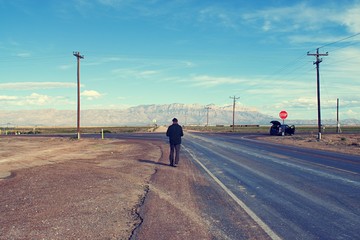 Lone person walking along road towards car with Guadalupe Mountains in distance