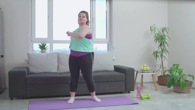 Active plus size female exercising home in morning, healthy lifestyle habit