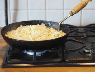 Cabbage is fried in a black cast iron pan on the kitchen stove.Natural home-made food.
