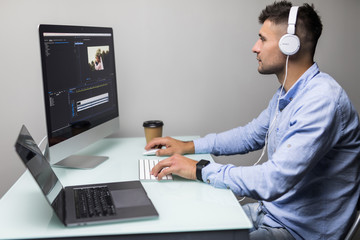 Confident man video editor works with footage in creative office studio.