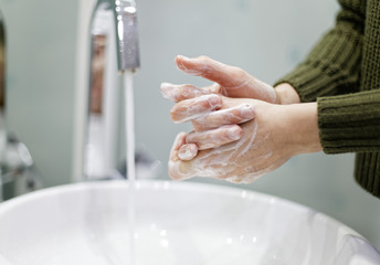 Woman washing hands in bathroom closeup